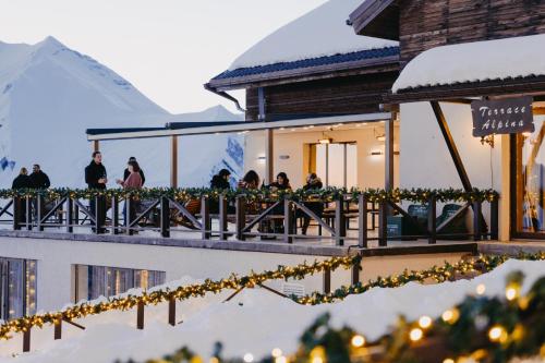 mensen op het balkon van een gebouw met sneeuw bij Alpina Hotel in Goedaoeri