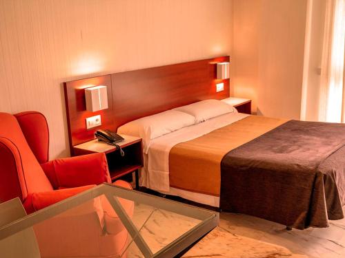セビリアにあるアパルタメントス ヴェルティス ビブ ランブラのベッドと椅子付きのホテルルーム