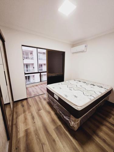 een slaapkamer met een bed en een groot raam bij Cobertura - Quadra Mar in Itapema