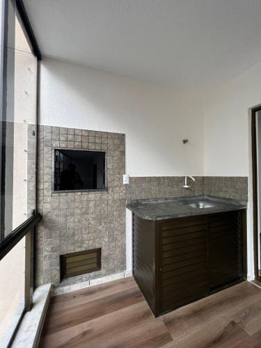 een badkamer met een wastafel en een flatscreen-tv bij Cobertura - Quadra Mar in Itapema