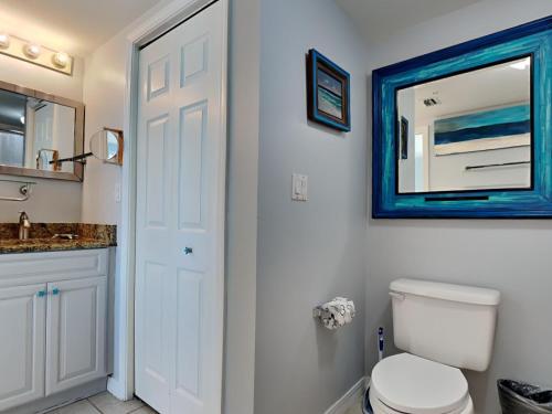 uma casa de banho com um WC branco e um espelho azul em Island Princess #705 em Fort Walton Beach
