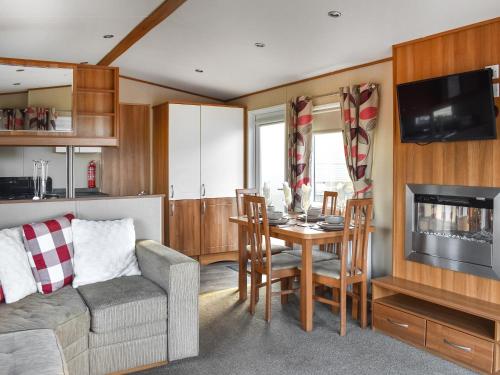 a living room with a couch and a table with a television at Solway View in Plumbland