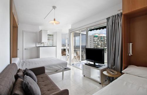 a hotel room with a couch and a tv and a bed at 1st Beach line Studio in Arroyo de la Miel