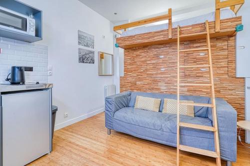 - un salon avec un canapé bleu en face d'un mur de briques dans l'établissement Charmant Studio Boulevard Voltaire - II, à Paris