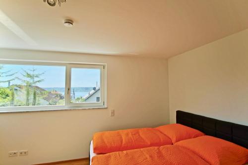 ein Schlafzimmer mit einem orangenen Bett und einem Fenster in der Unterkunft La Terrazza in Überlingen