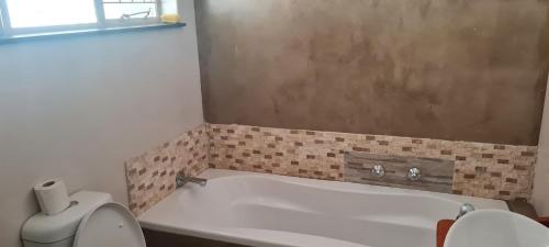 a bathroom with a bath tub and a toilet at Streetview Suites in Polokwane