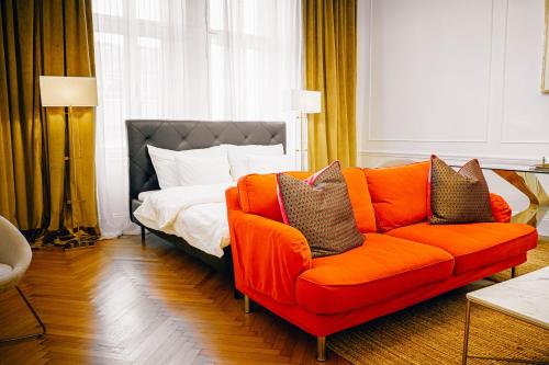 an orange couch in a room with a bed at Royal Residence Schönbrunn in Vienna