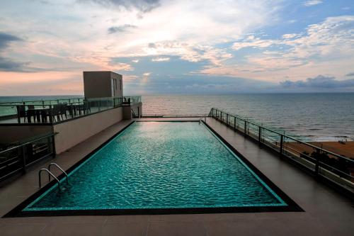 a swimming pool on the top of a building overlooking the ocean at Corundum Breeze Negombo in Negombo