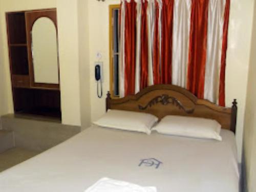 a bed with a wooden headboard in a room at Hotel Chancellor,Bhubaneswar in Bhubaneshwar