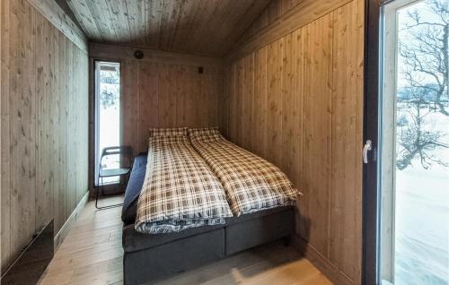 a bed in a room with wooden walls and a window at 3 Bedroom Nice Home In Vringsfoss in Maurset