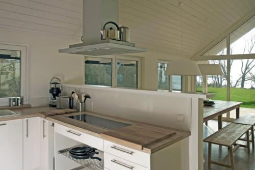 a white kitchen with a sink and a table at Ferienhäuser Boddenstrand in Wiek auf Rügen 
