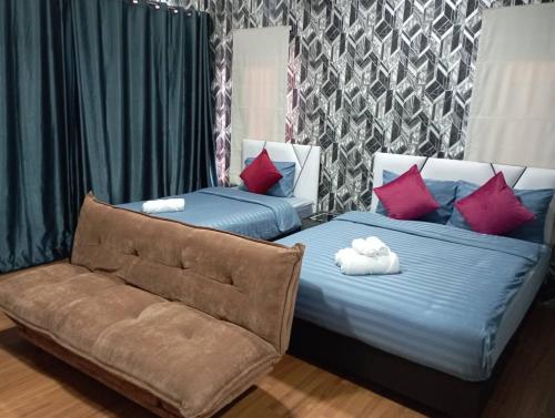 two beds with pillows and a couch in a room at Khokeng Room in Ban Ko