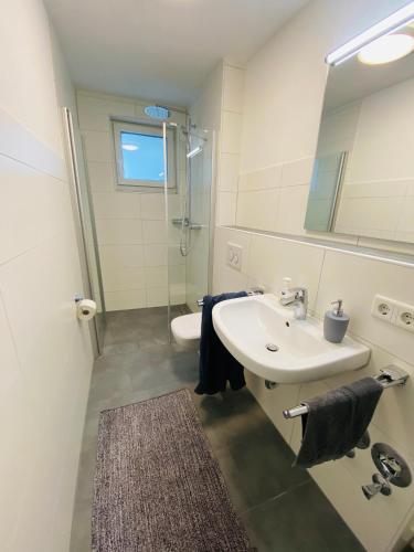 a white bathroom with a sink and a shower at Apartment Relax in Überlingen Bodensee in Überlingen
