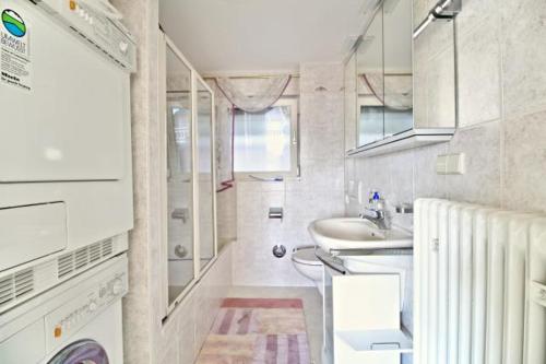ein kleines weißes Bad mit einem Waschbecken und einem Spiegel in der Unterkunft Seeterrasse mit Seeblick in Sipplingen
