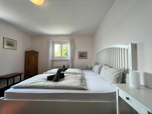 a bedroom with a large white bed with a window at Landhaus am See mit privatem Seezugang in Meersburg