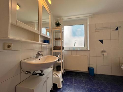 ein weißes Bad mit einem Waschbecken und einem Fenster in der Unterkunft Seewind in Überlingen