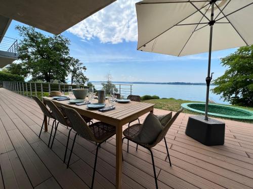 a wooden table with chairs and an umbrella on a deck at Villa am See mit privatem Seezugang in Meersburg