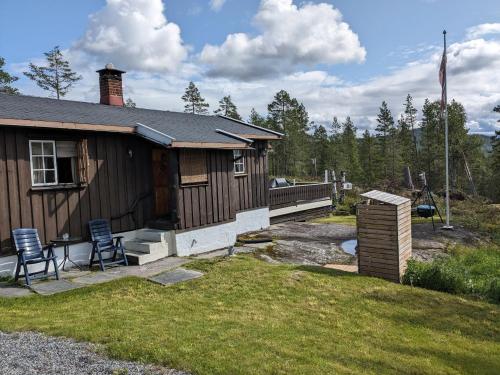 uma casa com duas cadeiras sentadas fora dela em Turibu - cabin in a nice hiking and skiing area em Kongsberg