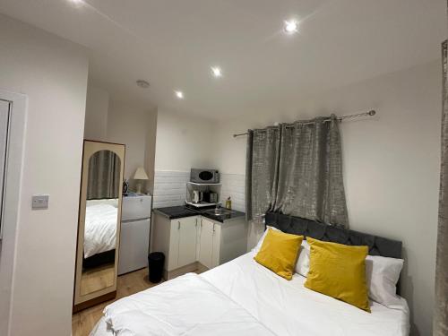 ブロムリーにある1st Studio Flat With full Private Toilet And Shower With its Own Kitchenette in Keedonwood Road Bromley A Fully Equipped Independent Studio Flatのベッドルーム(白いベッド、黄色い枕付)