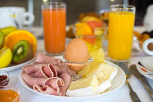 a table with a plate of food with eggs and cheese at The Originals City, Hotel Novella Premium, Nantes Est in Carquefou