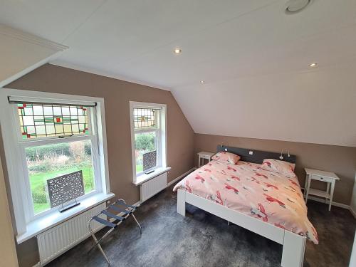 a bedroom with a bed and two windows at de Bloemenhof in Ouddorp