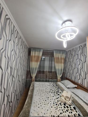 1 dormitorio con 1 cama grande y cortinas en уютная квартира, en Shymkent
