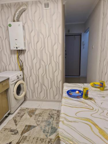 Habitación pequeña con cama y lavadora. en уютная квартира, en Shymkent
