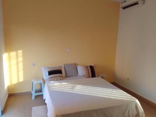 ein Schlafzimmer mit einem großen weißen Bett und einem Stuhl in der Unterkunft Hôtel Colibri in Niaga