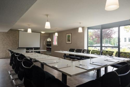 a conference room with tables and chairs and a screen at The Originals City, Hotel Novella Premium, Nantes Est in Carquefou