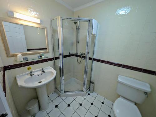 a bathroom with a shower and a toilet and a sink at Hitchin Priory Hotel in Hitchin