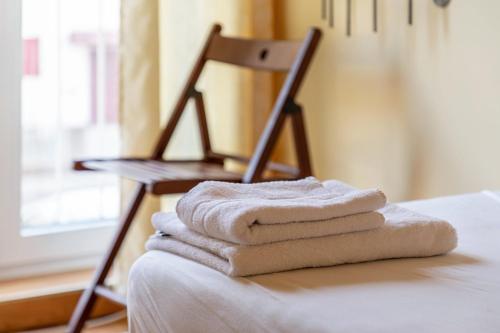 una pila de toallas sentadas en una cama junto a una silla en Ferienwohnung Links, en Welden