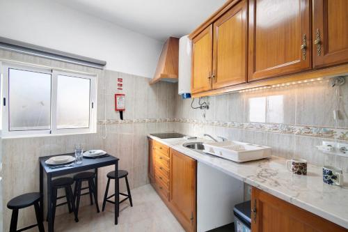 eine Küche mit Holzschränken und einem kleinen Tisch in der Unterkunft Casa da Vila nº4 in São Brás de Alportel