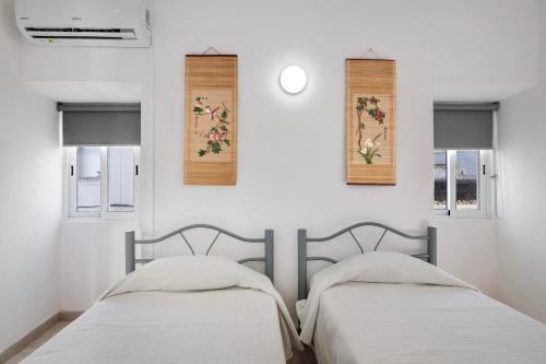 2 Betten in einem weißen Zimmer mit 2 Fenstern in der Unterkunft Casa da Vila nº4 in São Brás de Alportel