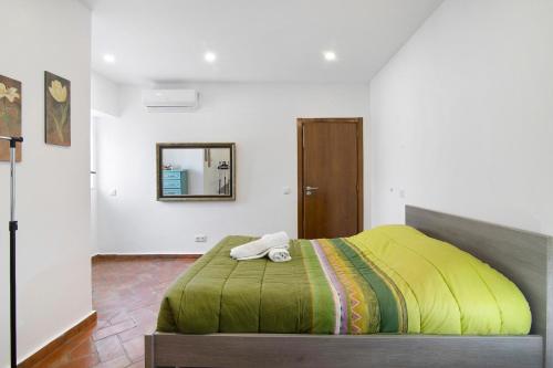 a bedroom with a green bed with a mirror at Casa da Vila nº 6 in São Brás de Alportel