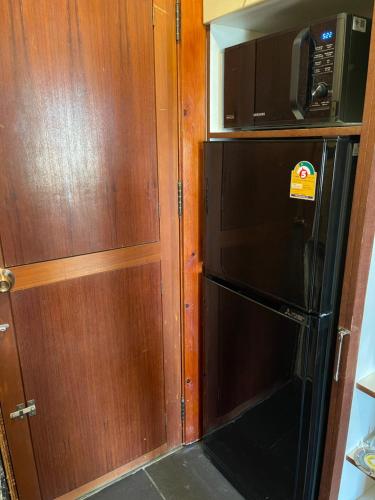 a kitchen with a black refrigerator and a microwave at Jomtien Condotel Condominium in Pattaya South