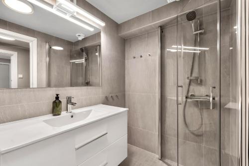 La salle de bains est pourvue d'une douche, d'un lavabo et d'un miroir. dans l'établissement Bispegata 5 - Studio Apartment hotel, à Tromsø