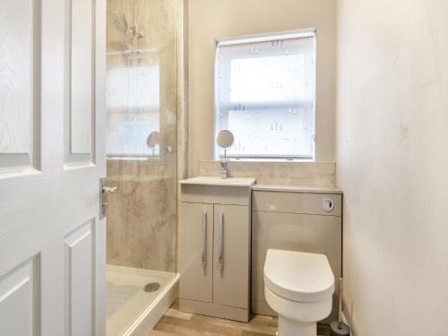 uma casa de banho com um WC, um lavatório e uma janela em Horseshoe Cottage em Skegness