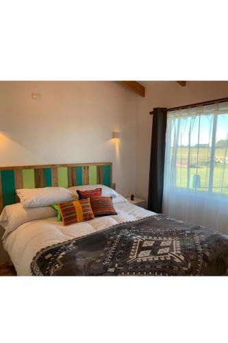 una camera da letto con letto, cuscini e finestra di El Tambo del Anakiri a Los Muermos