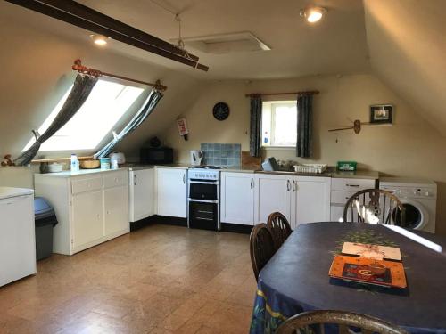 cocina con armarios blancos, mesa y ventana en Stable Cottage, Ardnadrochet en Lochdon