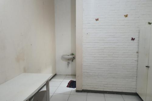 ein Bad mit einem WC und einer weißen Wand in der Unterkunft OYO 93448 Padang Pasir Homestay in Surabaya