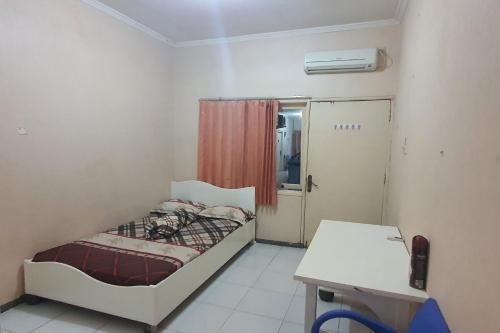 Kleines Zimmer mit einem Bett und einem Schreibtisch. in der Unterkunft OYO 93448 Padang Pasir Homestay in Surabaya