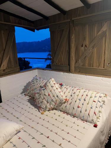 a bed in the back of a boat with a window at Suíte e sala - Vista Barra do Sahy in São Sebastião