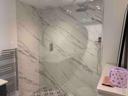 a bathroom with a shower with white marble at Private Apartment at Woodland Retreat in Gamlingay