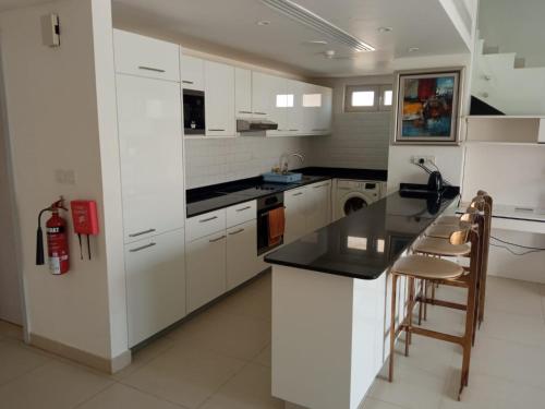a kitchen with white cabinets and a black counter top at As sifah in As Sīfah