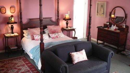 a bedroom with a bed and a couch and a mirror at The Lighthouse Guesthouse in Colesberg