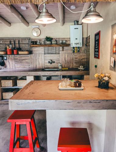 a kitchen with a table and two red stools at La Saucina - Cabaña Rústica Chic in Tunuyán