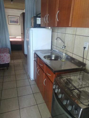 a kitchen with a sink and a white refrigerator at Residencial do Tchê in Florianópolis