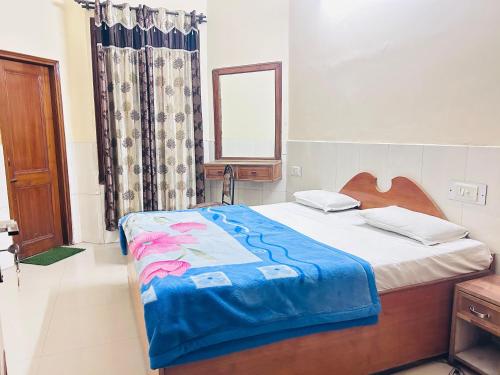 a bedroom with a bed with a blue blanket on it at Sunrise hotel in Jalandhar
