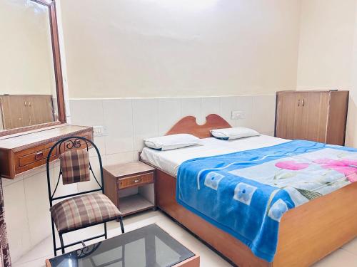 a bedroom with a bed and a chair and a mirror at Sunrise hotel in Jalandhar
