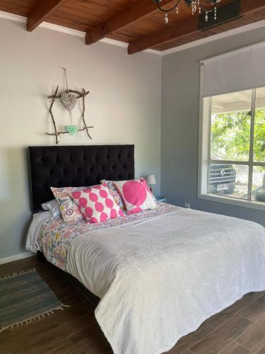 a bedroom with a large bed with pink pillows at Agradable casa con Tina de agua Caliente y Piscina in Quillón
